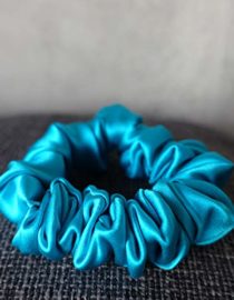 Blue Colored Silk Scrunchie Kept On A Grey Colored Fabric