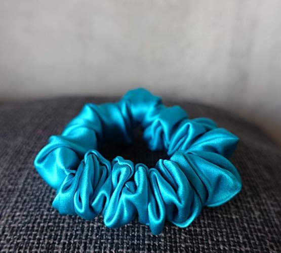 Blue Colored Silk Scrunchie Kept On A Grey Colored Fabric