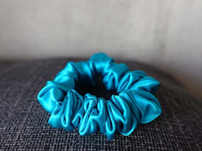 Blue Colored Silk Scrunchie Kept On A Grey Colored Fabric