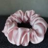 Pink Colored Silk Scrunchie Kept On A Grey Colored Fabric