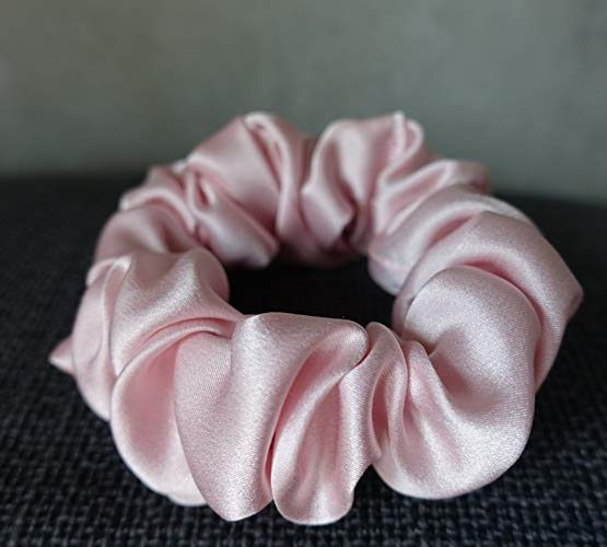 Pink Colored Silk Scrunchie Kept On A Grey Colored Fabric
