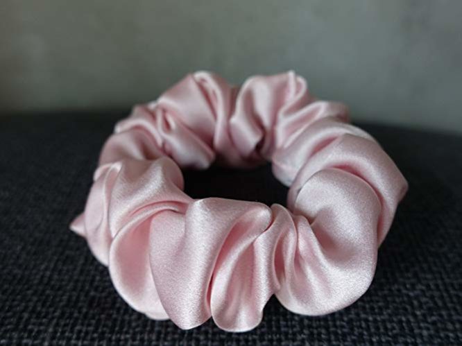 Pink Colored Silk Scrunchie Kept On A Grey Colored Fabric