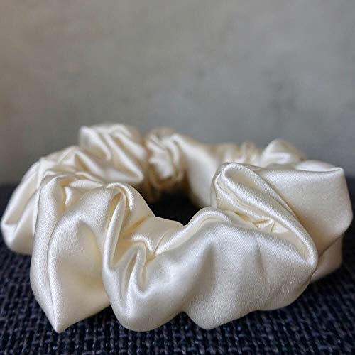 White Colored Silk Scrunchie Kept On A Grey Colored Fabric